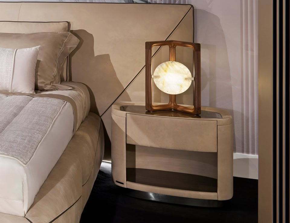 Leather bedside table with curved edges beside upholstered bed