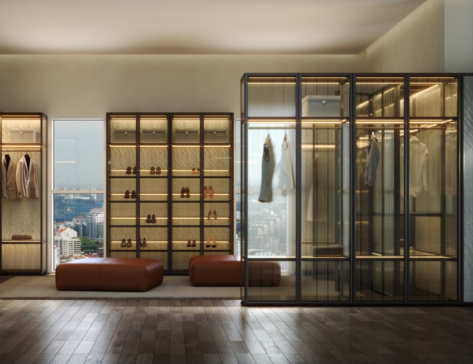 Glass and metal walk-in wardrobe with shelving and hanging space in bedroom setting