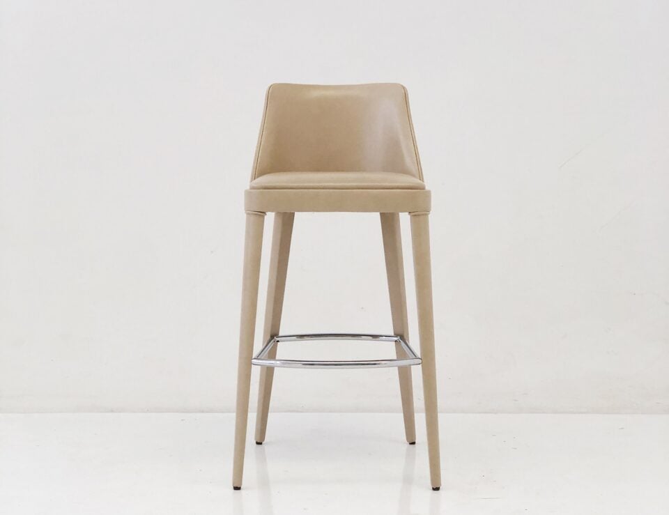Beige leather stool with metal footrest on white floor