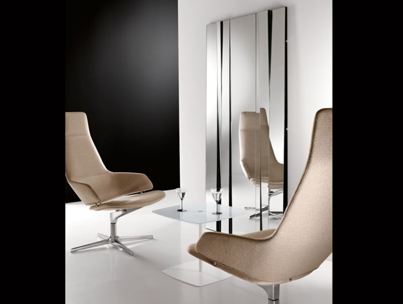 Beige fabric swivel lounge chairs with metal bases beside glass table