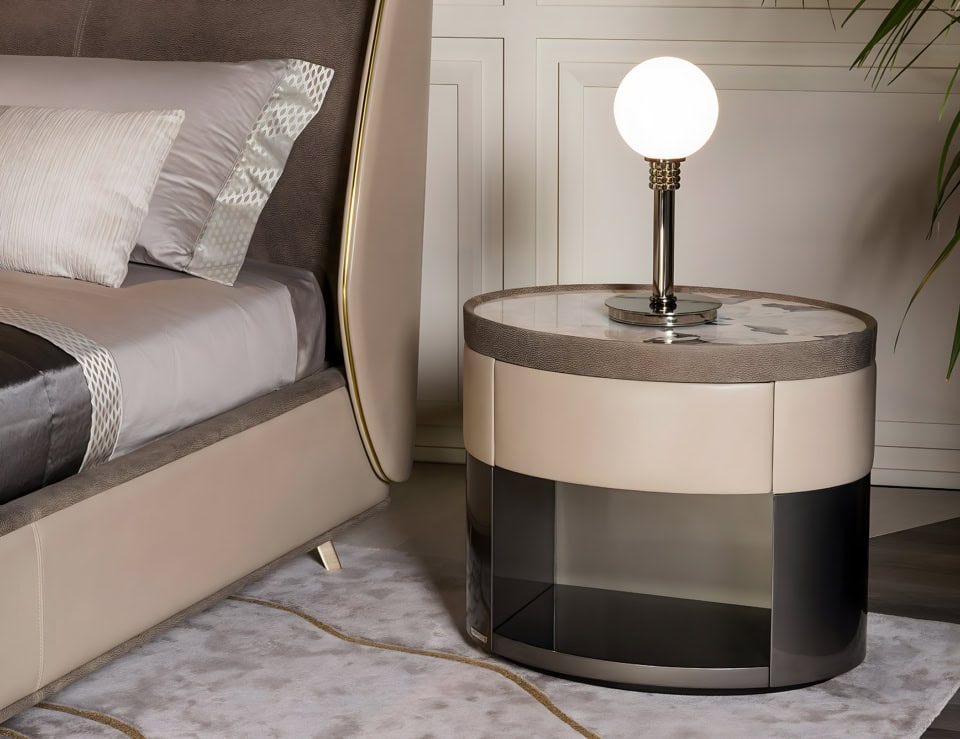 Round leather bedside table with marble top beside bed