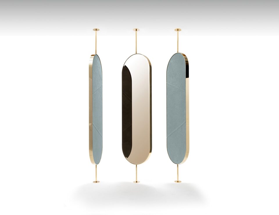 Metal and mirrored glass oval mirrors with gold frame mounted between floor and ceiling.