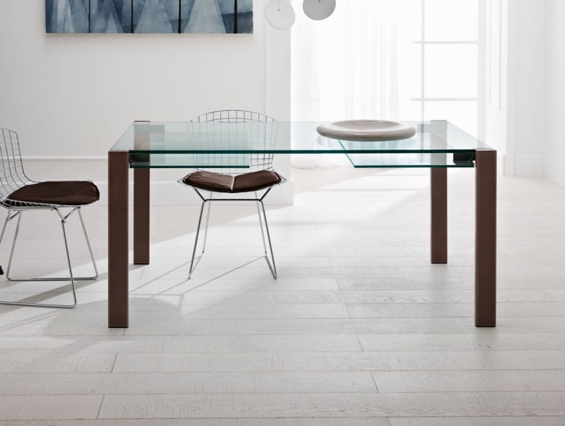 Glass dining table with brown metal legs in a bright room