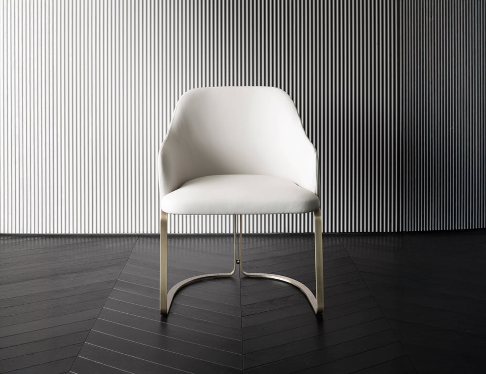 Leather dining chair with curved metal legs on dark floor