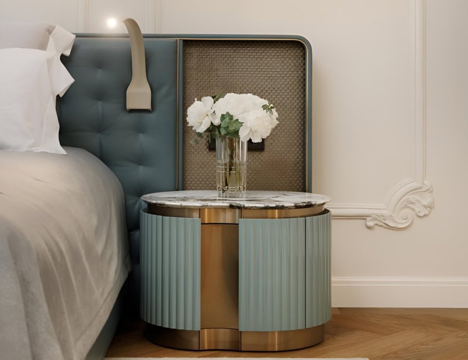Fabric bedside table with round marble top and metal base beside bed