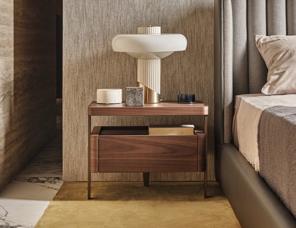 Wood bedside table with eucalyptus finish beside upholstered bed