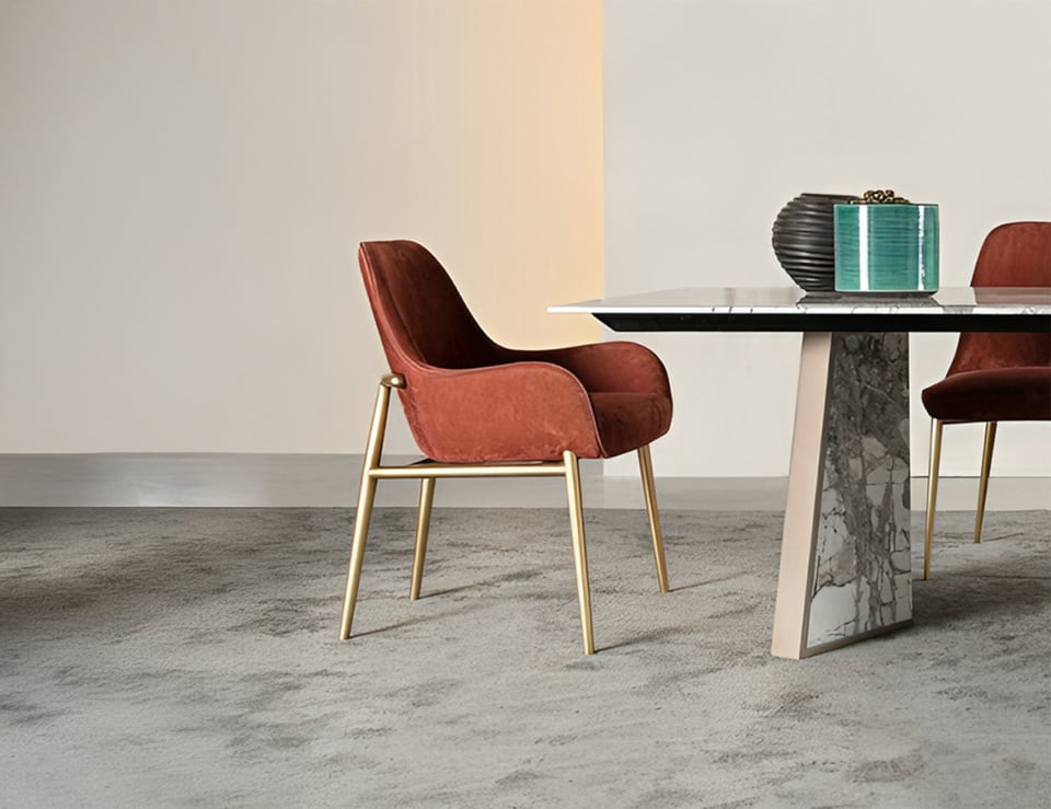 Fabric dining chair with arms and metal legs beside a marble dining table